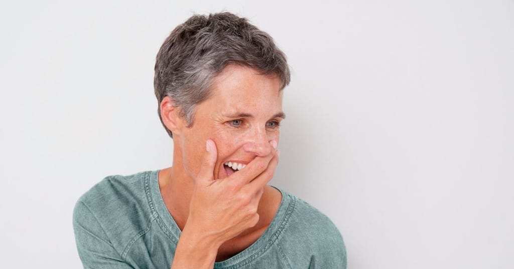 woman laughing holding hand over mouth