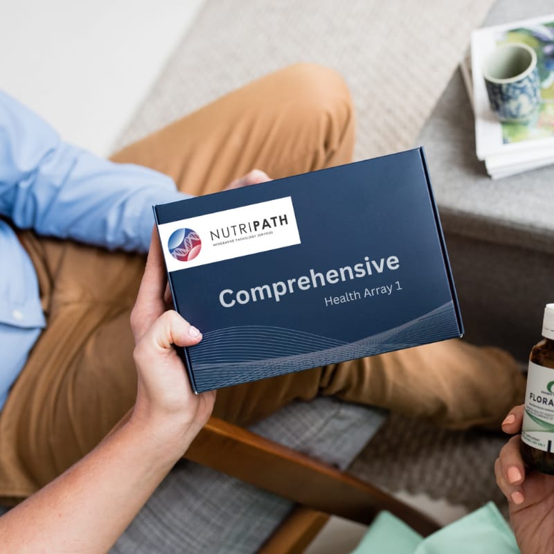 A woman holding a test kit box for the comprehensive health array by Nutripath, looking forward to understanding her body more thanks to 240 biomarkers being reported on