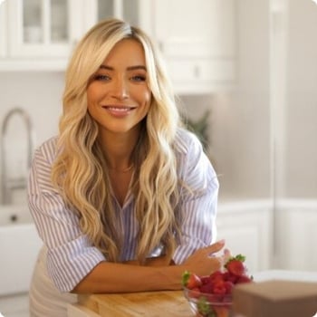 aggie-lal young woman leaning on kitchen bench next to bowl of fresh strawberries