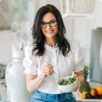 dr-mary-claire-haver vibrant woman in kitchen holding bowl of green salad and fork