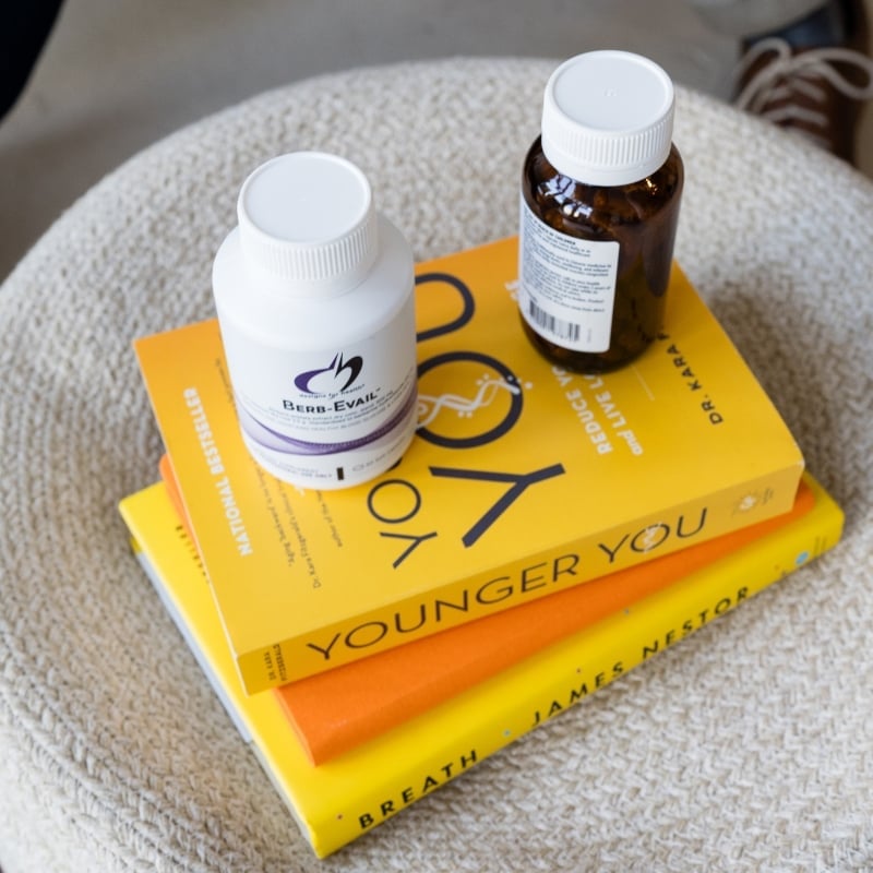 health-book-stack-with-supplements practitioner jabe and health coach bee sitting on a couch discussing lab results.