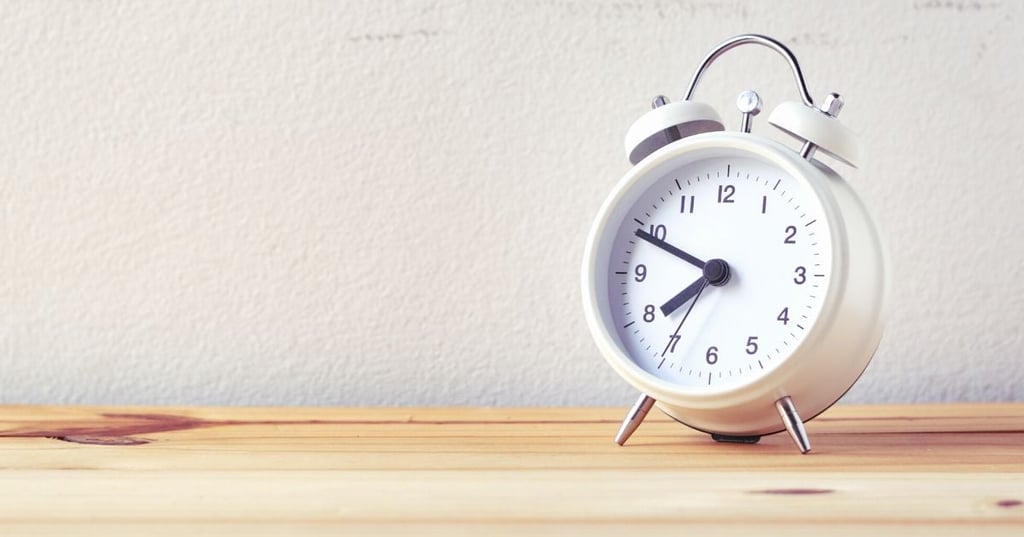 how-old-are-you-really-open-graph simple white alarm clock positioned on wooden shelf