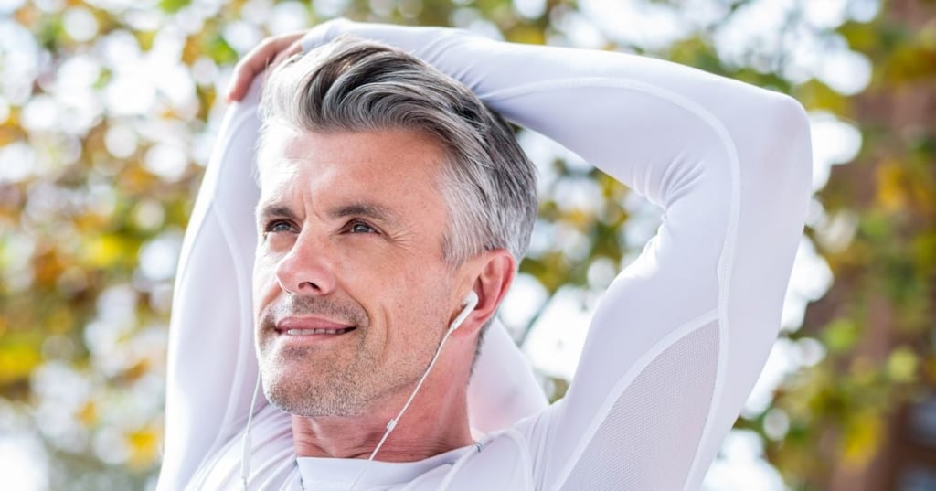 fit middle aged man standing outside stretching arms overhead