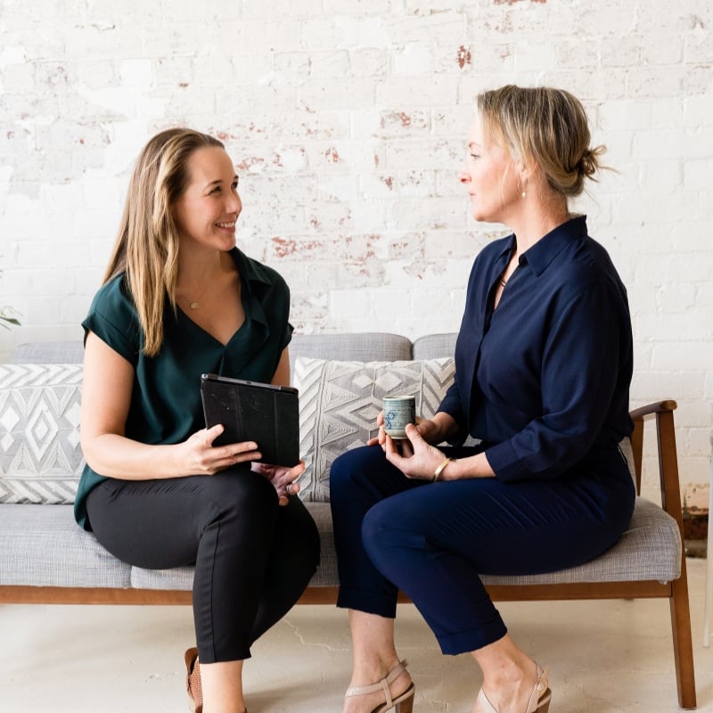 jess-bee-coaching-session practitioner jabe and health coach bee sitting on a couch discussing lab results.