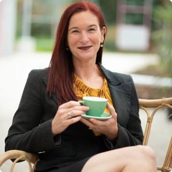 marie-mcleod woman in midlife sitting outside on cane chair holding cup and saucer