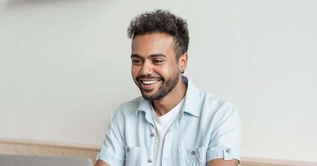 methylation-open-graph young man smiling sitting at table looking at laptop
