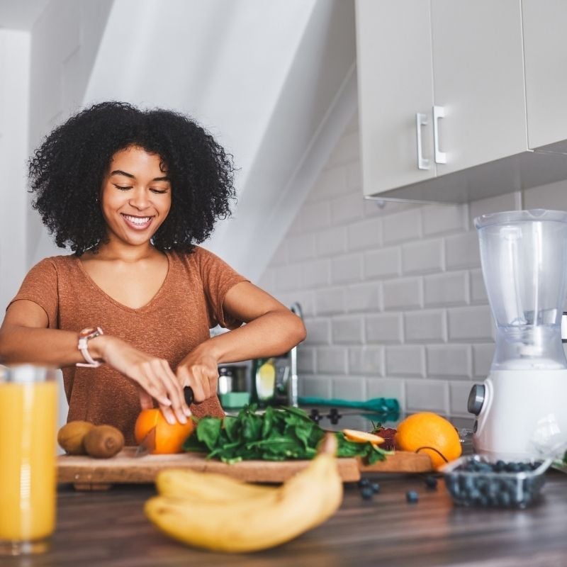 A healthy woman in her kitchen cutting an orange
