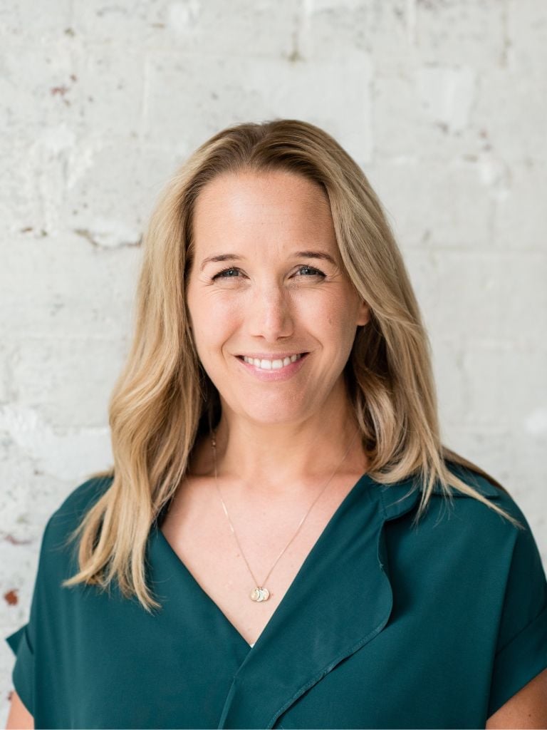 jessica cairns health coach wearing dark green shirt standing smiling