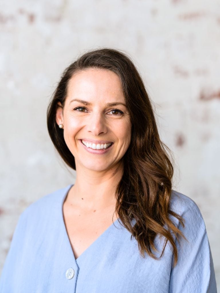 liv brown health coach wearing sky blue shirt standing smiling