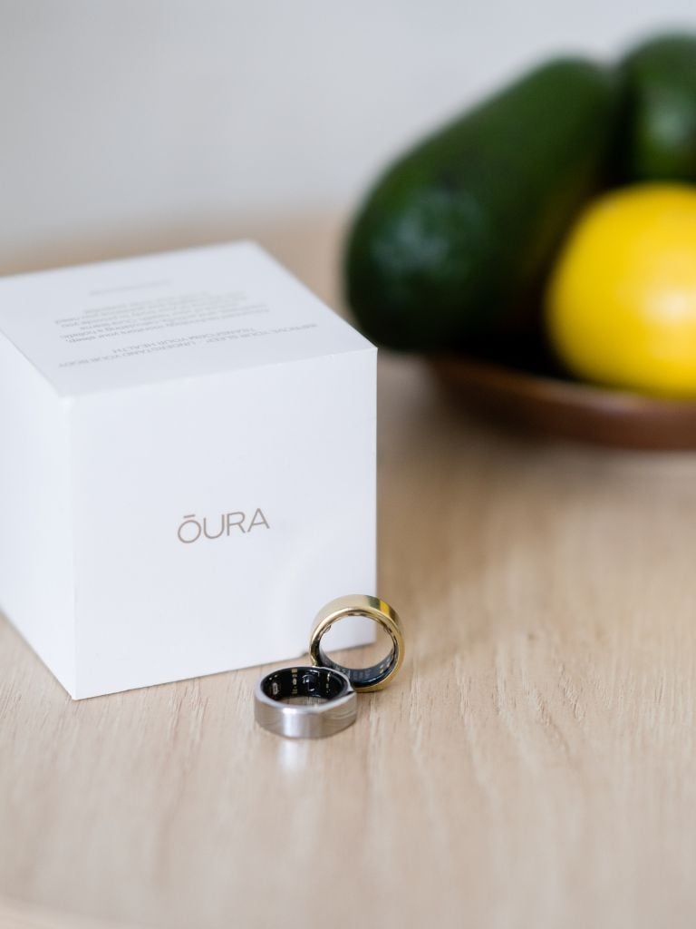 oura ring box displayed on wooden table next to one gold and one silver oura ring